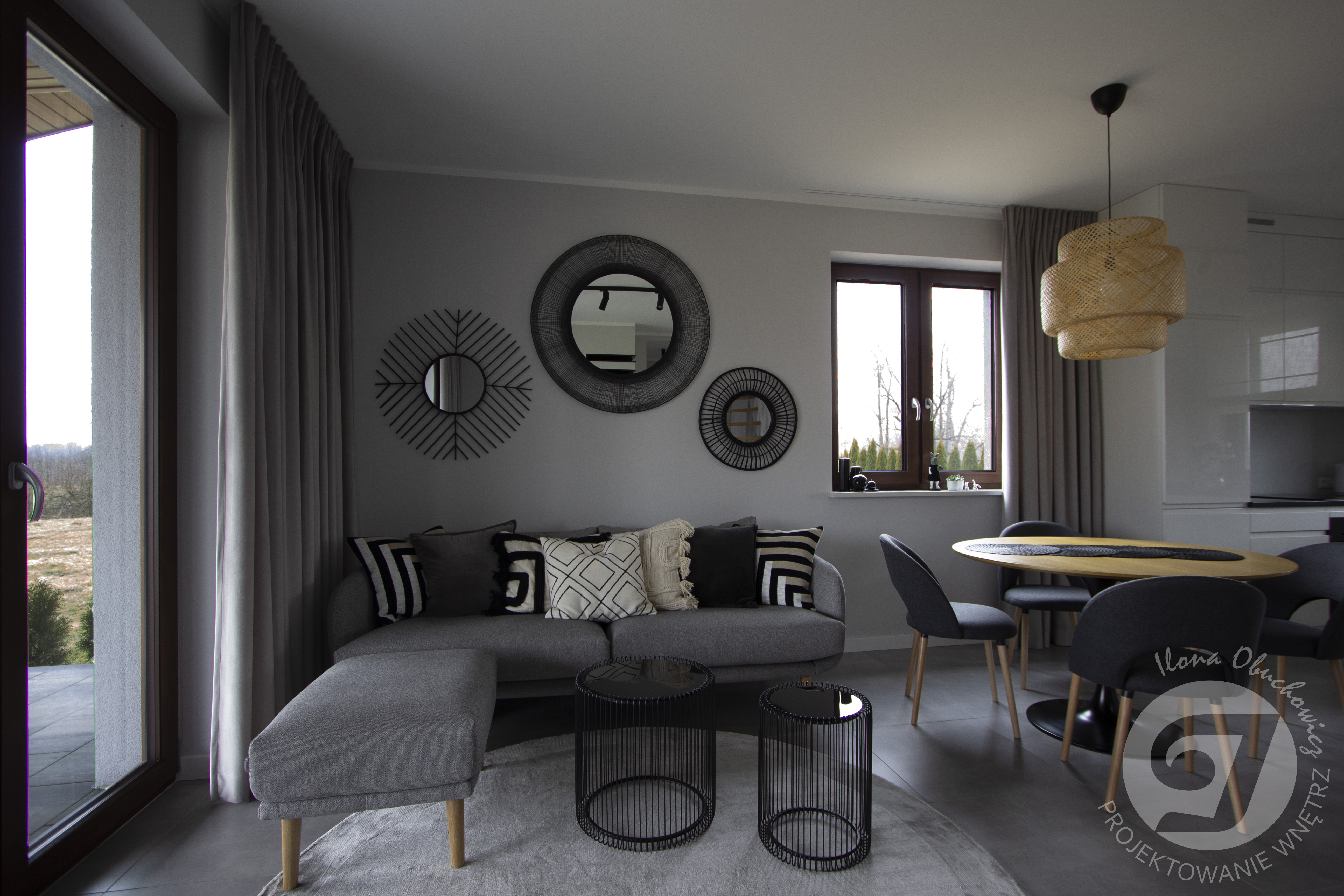 przytulny salon w odcieniach szarości, z okrągłymi lustrami, okrągłym drewnianym stołem, wisząca lampą Ikea w stylu boho